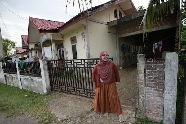 Qurrata Ayuni, a 28-year-old tsunami survivor, stands outside her house, built on the same spot where her parents' home once stood before it was destroyed by the disaster in 2004 in Lampuuk on the outskirts of Banda Aceh, Indonesia, Friday, Dec. 13, 2024. (AP Photo/Achmad Ibrahim)