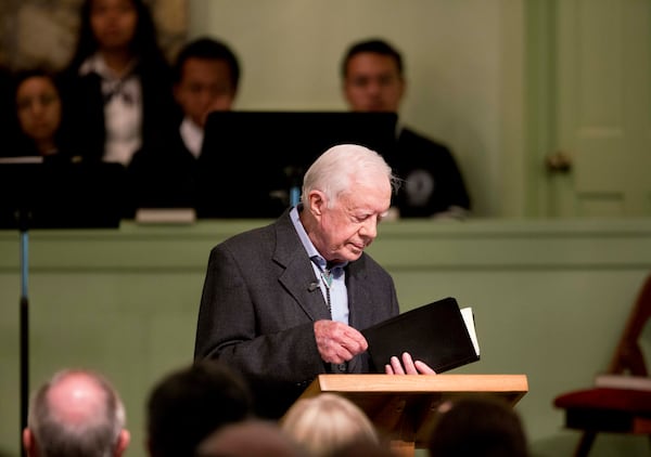 FILE - Former President Jimmy Carter opens up a Bible while teaching Sunday school class at Maranatha Baptist Church in his hometown, Aug. 23, 2015, in Plains, Ga. (AP Photo/David Goldman, File)