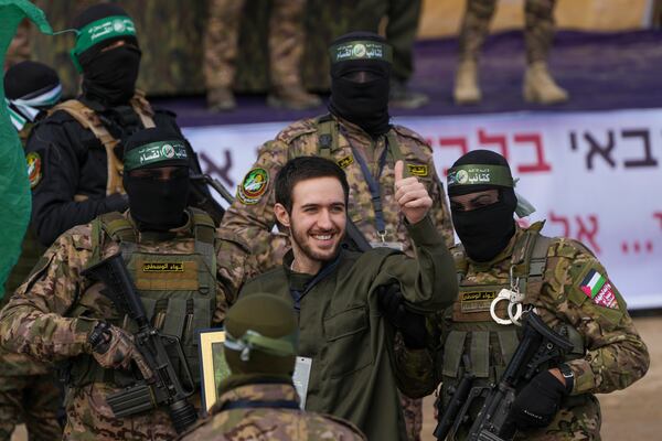 Israeli hostage Omer Shem, centre, is escorted by Hamas fighters before being handed over to the Red Cross in Nuseirat, central Gaza Strip, Saturday, Feb. 22, 2025. (AP Photo/Abdel Kareem Hana)