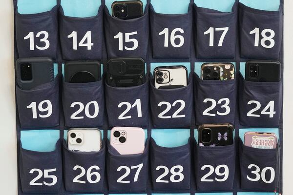 FILE- A phone holder hangs in a classroom at Delta High School, Friday, Feb. 23, 2024, in Delta, Utah. (AP Photo/Rick Bowmer, file)