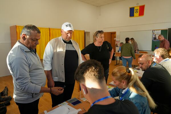 People register before voting in the first round of the presidential election redo in Bucharest, Romania, Sunday, May 4, 2025. (AP Photo/Vadim Ghirda)