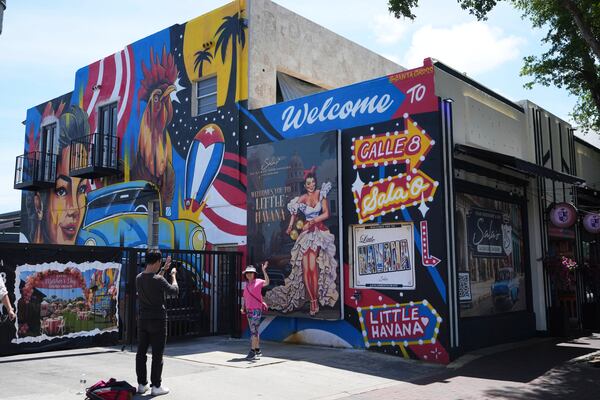 People take photographs next to a mural featuring a rooster on Calle Ocho in the Little Havana neighborhood of Miami, Wednesday, May 7, 2025. (AP Photo/Lynne Sladky)