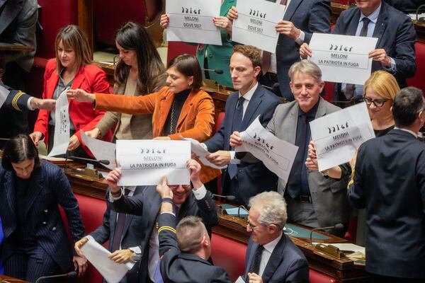 Opposition members of parliament display placards in Italian reading "Meloni the patriot at large", during a debate in the Italian lower Chamber in Rome, Wednesday, Feb. 5, 2025, over the controversial repatriation, last week, of a Libyan warlord, Ossama Anjiem, also known as Ossama al-Masri, wanted by the International Criminal Court in the Hague, and who had been arrested in Turin, northern Italy. (AP Photo/Gregorio Borgia)