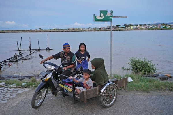 A family aride on a motorized tricycle on Ulee Lheue beach, one of the ares hardest hit by the Indian Ocean tsunami in 2004, in Banda Aceh, Indonesia, Friday, Dec. 13, 2024. (AP Photo/Achmad Ibrahim)