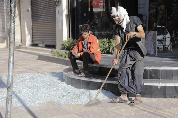 Yemenis clean debris in front of their shops after a U.S. airstrikes in Sanaa, Yemen, Sunday, March 16, 2025. (AP Photo/Osamah Abdulrahman)