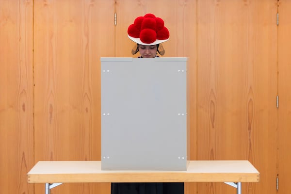 A young woman in traditional Black Forest costume with a Bollenhut (Bollenhat) stands in the voting booth at a polling station in Gutach, Germany, Sunday, Feb. 23, 2025, during the national election. (Philipp von Ditfurth/dpa via AP)