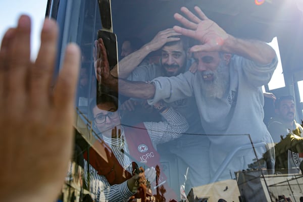 Freed Palestinian prisoners wave from a bus as they arrive in the Gaza Strip after being released from an Israeli prison following a ceasefire agreement between Hamas and Israel in Khan Younis, Saturday, Feb. 1, 2025. (AP Photo/Jehad Alshrafi)