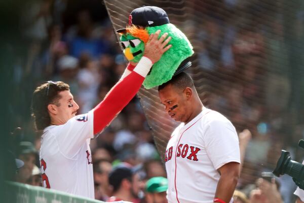 Boston Red Sox's Jarren Duran, left, crowns teammate Rafael Devers with a "Wally the Green Monster" head that the team uses for their celebration after a home run following Devers' homer in the seventh inning baseball game against the Texas Rangers, Thursday May 8, 2025 in Boston. (AP Photo/Jim Davis)
