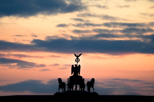 The sun rises at the Brandenburg Gate early morning on the day of Germany's national election in Berlin, Germany, Sunday, Feb. 23, 2025. (AP Photo/Markus Schreiber)