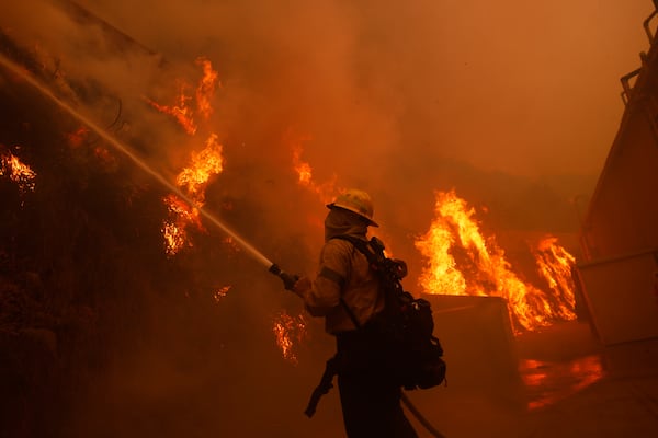 A firefighter battles the advancing Palisades Fire around a structure in the Pacific Palisades neighborhood of Los Angeles Tuesday, Jan. 7, 2025. (AP Photo/Etienne Laurent)