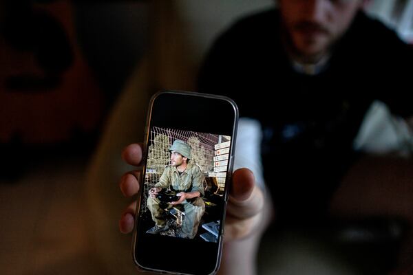 Yotam Vilk shows a photo of himself on the Israel-Gaza border during army reserve duty before he joined a growing number of Israeli soldiers speaking out against the 15-month conflict and refusing to continue fighting, at home in Tel Aviv, Israel, on Friday, Jan. 10, 2025. (AP Photo/Maya Alleruzzo)