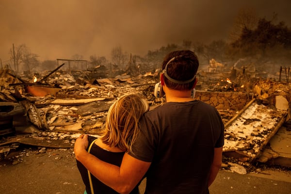 Megan Mantia, left, and her boyfriend Thomas, return to Mantia's fire-damaged home after the Eaton Fire swept through, Wednesday, Jan. 8, 2025, in Altadena, Calif. (AP Photo/Ethan Swope)