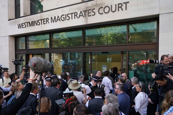 Russell Brand escorted by police and surrounded by the media arrives at Westminster Magistrates' court in London, Friday, May 2, 2025, where he faces, rape and sexual assault charges involving four women. (AP Photo/Alberto Pezzali)