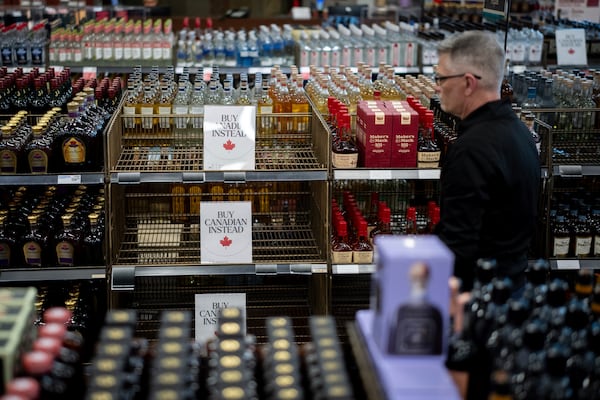 A liquor store employee looks at a sign placed in the American whiskey section at a B.C. Liquor Store after top selling American made products have been removed from shelves in Vancouver, B.C., Sunday, Feb. 2, 2025. (Ethan Cairns/The Canadian Press via AP)