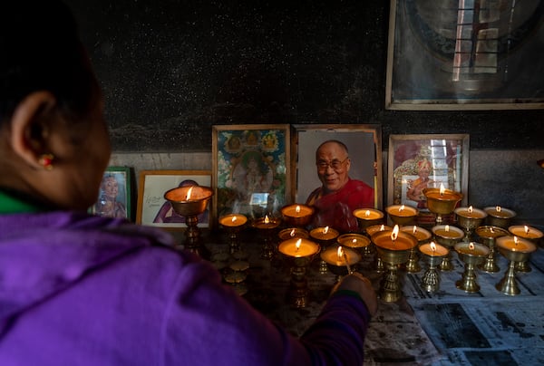 A Tibetan woman lights a butter lamp and offers a prayer in the remembrance of those who lost their lives in the recent earthquake, at a Tibetan camp in Lalitpur, Nepal, on Wednesday, Jan. 8, 2025. (AP Photo/Niranjan Shrestha)