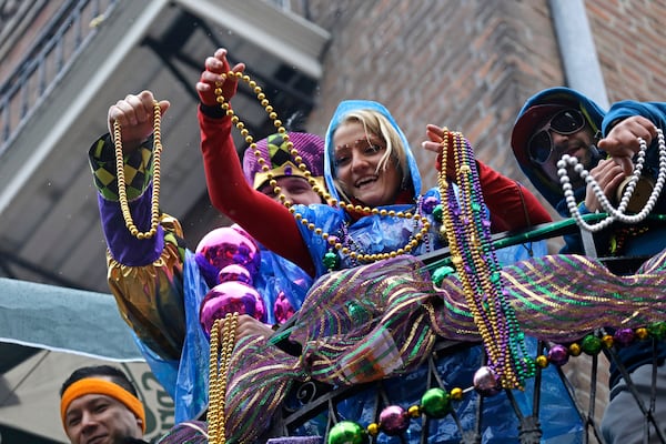 FILE - Revelers throw beads from balconies in the rain during Mardi Gras festivities in the French Quarter in New Orleans, March 4, 2014. AP Photo/Gerald Herbert, File)