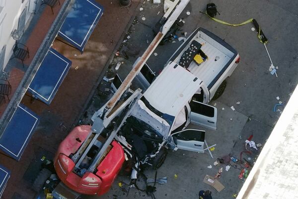 A black flag with white lettering lies on the ground rolled up behind a pickup truck that a man drove into a crowd on Bourbon Street in New Orleans, killing and injuring a number of people, early Wednesday morning, Jan. 1, 2025. The FBI said they recovered an Islamic State group flag, which is black with white lettering, from the vehicle. (AP Photo/Gerald Herbert)