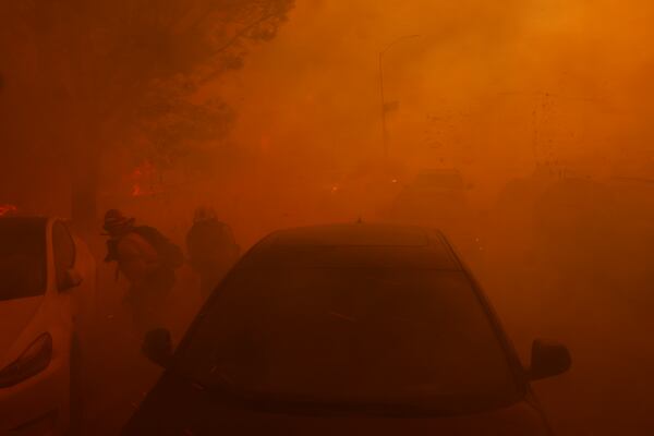 A pair of firefighters try to protect themselves from flying embers from the Palisades Fire in the Pacific Palisades neighborhood of Los Angeles Tuesday, Jan. 7, 2025. (AP Photo/Etienne Laurent)