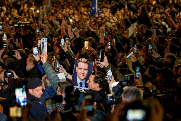 Supporters of presidential candidate Nicusor Dan cheer holding an electoral poster after he won the second round of the country's presidential election redo in Bucharest, Romania, early Monday, May 19, 2025. (AP Photo/Andreea Alexandru)