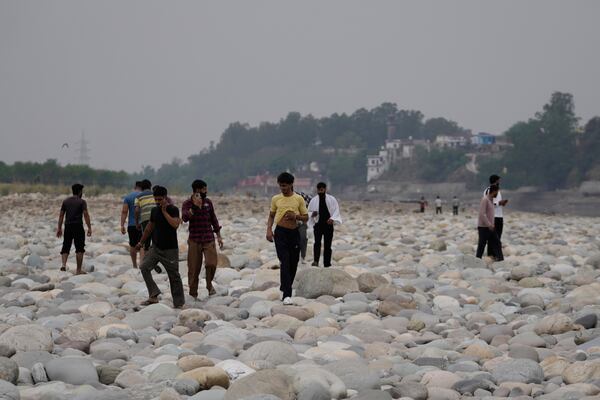 People cross the Chenab River after the flow of water was halted from a dam, at Akhnoor, on the outskirts of Jammu, India, Monday, May 5, 2025. (AP Photo/Channi Anand)