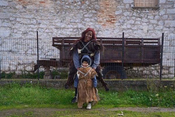 Vasiliki Pergada poses with her four year old daughter Panagiota for a portrait, dressed in animal skins and heavy bronze bells, as part of carnival celebrations in Distomo, a village in central Greece, on Monday, March 3, 2025. (AP Photo/Petros Giannakouris)