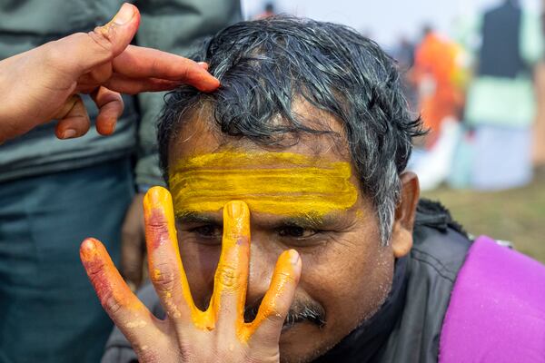 A Hindu devotee gets sacred marks painted on his forehead by a priest at the confluence of the Ganges, the Yamuna, and the Saraswati rivers on the first day of the 45-day-long Maha Kumbh festival in Prayagraj, India, Monday, Jan. 13, 2025. (AP Photo/Ashwini Bhatia)