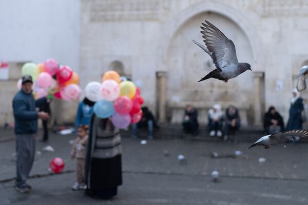 Pigeons fly by as a vendor sells balloons near Al-Hamidiyeh Souq on New Years Eve, in Damascus, Syria, Tuesday, Dec. 31, 2024. (AP Photo/Mosa'ab Elshamy)