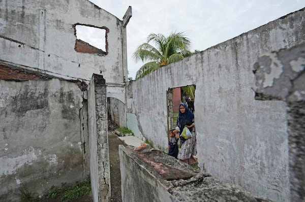 A woman walks trough an opening on the wall of a building badly damaged during the Indian Ocean tsunami in 2004 in Banda Aceh, Aceh province, Indonesia, Saturday, Dec 14, 2024. (AP Photo/Achmad Ibrahim)