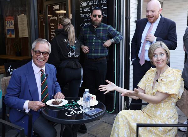 Reform UK leader Nigel Farage and Reform UK mayoral candidate Andrea Jenkyns look towards the media as they have a cream tea break during their election campaign in Scunthorpe, England, Tuesday, April 29, 2025. (AP Photo/Darren Staples)