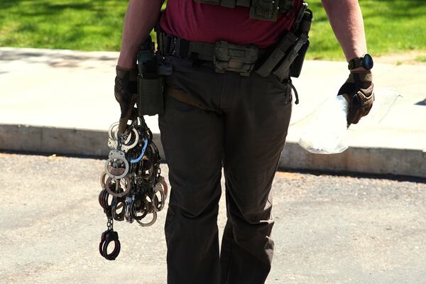 A federal agent holds handcuffs outside an immigration court, Wednesday, May 21, 2025, in Phoenix. (AP Photo/Ross D. Franklin)