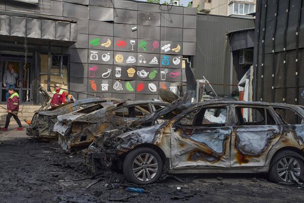 Municipal workers clean up near burnt cars in the residential area following Russia's drone attack in Kyiv, Ukraine, Sunday, May 4, 2025. (AP Photo/Efrem Lukatsky)