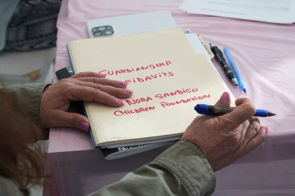 Nora Sandigo holds a folder with documents signed by families giving her legal guardianship of their children, Sunday, Jan. 19, 2025, in Miami. Since December, Sandigo has become the legal guardian of at least 30 children. She has been doing so for 15 years and is the legal guardian to more than 2,000 children. (AP Photo/Marta Lavandier)