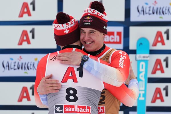 Switzerland's Alexis Monney, back to camera, bronze medalist in a men's downhill race, hugs gold medalist Switzerland's Franjo von Allmen, at the Alpine Ski World Championships, in Saalbach-Hinterglemm, Austria, Sunday, Feb. 9, 2025. (AP Photo/Giovanni Auletta)