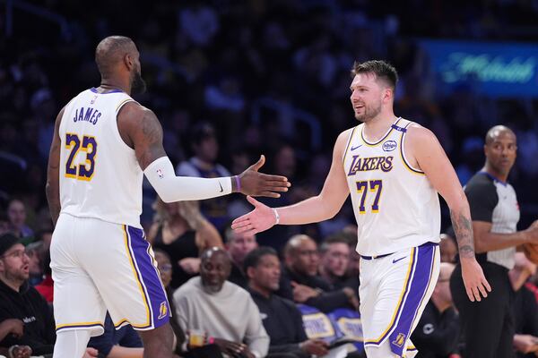 Los Angeles Lakers forward LeBron James, left, and guard Luka Doncic slap hands as Doncic comes out of the game and James comes in during the second half of an NBA basketball game against the Los Angeles Clippers, Sunday, March 2, 2025, in Los Angeles. (AP Photo/Mark J. Terrill)