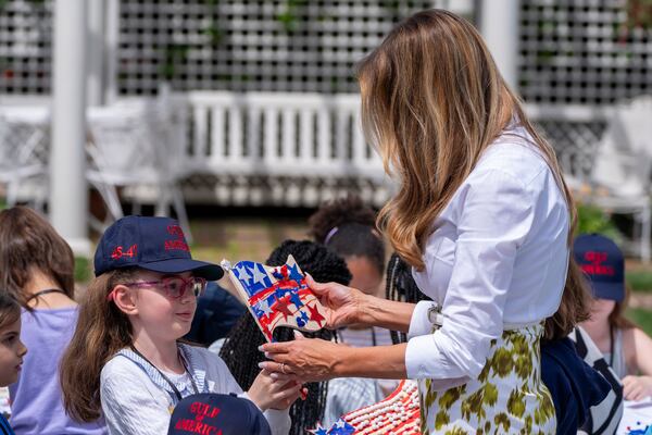 First lady Melania Trump looks at a decorated flag as she participates in flag decorating during a Take Our Child to Work Day event in the Jacqueline Kennedy Garden at the White House, Tuesday, May 20, 2025, in Washington. (AP Photo/Alex Brandon)