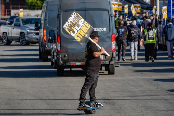 UPS driver Jhon Solidum, a member of the Teamsters union, rides a one wheeler to support the Amazon workers striking outside an Amazon Fulfillment Center as Teamsters seek labor contract nationwide, Thursday, Dec. 19, 2024, in City of Industry, Calif. (AP Photo/Damian Dovarganes)