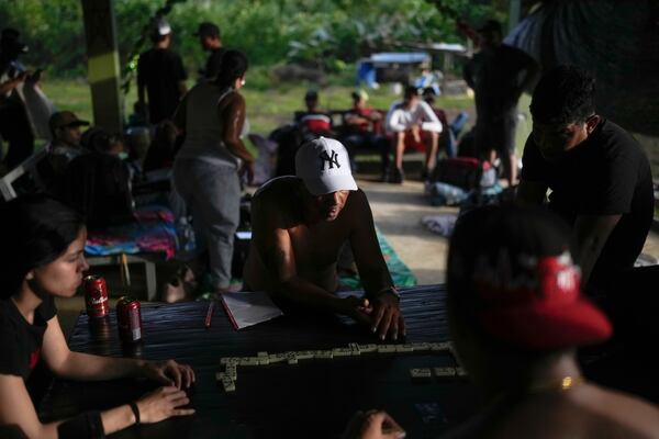 Venezuelan migrants play dominoes in Puerto Carti, on Panama's Caribbean coast, Saturday, Feb. 22, 2025, where they plan to board boats to Colombia after turning back from southern Mexico where they gave up hopes of reaching the U.S. amid President Trump's crackdown on migration. (AP Photo/Matias Delacroix)