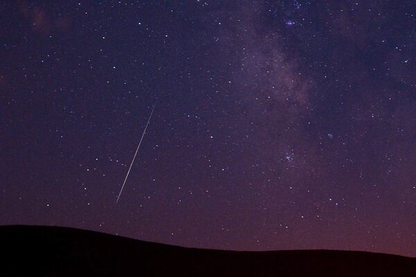 FILE - A Perseid meteor streaks across the sky during the Perseid meteor shower in Vinton, California, Aug. 11, 2009. (AP Photo/Kevin Clifford, File)