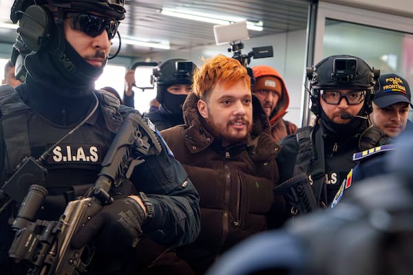 Mohamed Amra, nicknamed ''The Fly", is escorted by armed police officers at the Henri Coanda international airport in Otopeni, Romania, Tuesday, Feb. 25, 2025, before being extradited to France. (AP Photo/Vadim Ghirda)