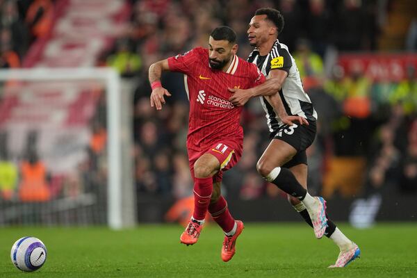 Newcastle's Jacob Murphy, right, challenges Liverpool's Mohamed Salah during the English Premier League soccer match between Liverpool and Newcastle United at Anfield in Liverpool, Wednesday, Feb. 26, 2025. (AP Photo/Jon Super)