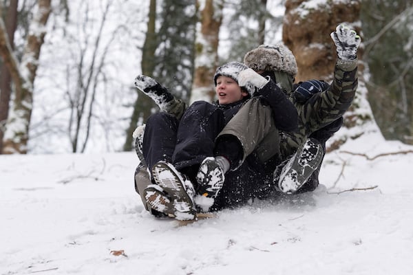 From left, Elijah, Jackson and Malian ride on a sled together down a hill at Laurelhurst Park on Thursday, Feb. 13, 2025, in Portland, Ore. (AP Photo/Jenny Kane)