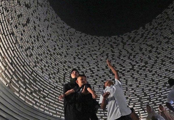 Visitors looks at a wall displaying the names of the victims of 2004 Indian Ocean tsunami, at the Tsunami Museum in Banda Aceh, Aceh province, Indonesia, Saturday, Dec 14, 2024. (AP Photo/Achmad Ibrahim)