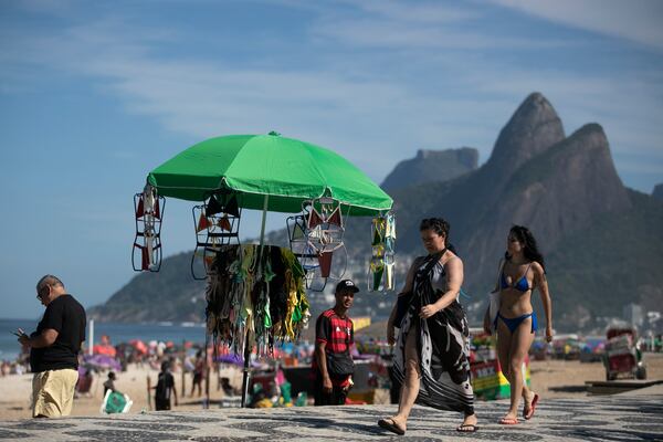 Beachgoers walk past a vendor's stand of beachwear on Ipanema Beach in Rio de Janeiro, Sunday, May 25, 2025. (AP Photo/Bruna Prado)