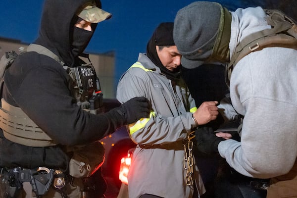 U.S. Immigration and Customs Enforcement officers use a chain to more comfortably restrain a detained person using handcuffs positioned in front, Monday, Jan. 27, 2025, in Silver Spring, Md. (AP Photo/Alex Brandon)