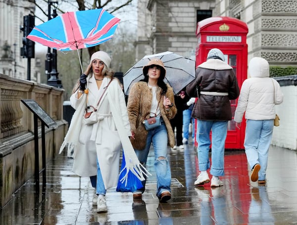 A woman has her umbrella upturned by the wind whilst walking near Parliament Square, London, Sunday Jan. 5, 2025. (Jonathan Brady/PA via AP)