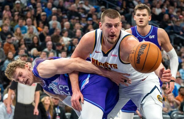 Denver Nuggets center Nikola Jokic, front right, becomes entangled with Utah Jazz forward Lauri Markkanen (23) as Jazz center Walker Kessler, back right, looks on during the first half of an NBA basketball game Monday, Dec. 30, 2024, in Salt Lake City. (AP Photo/Rick Egan)