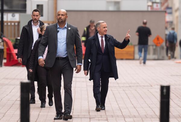 Prime Minister Mark Carney waves to a member of the public as he walks through downtown during a news conference, in Ottawa, Friday, May 2, 2025. (Adrian Wyld /The Canadian Press via AP)