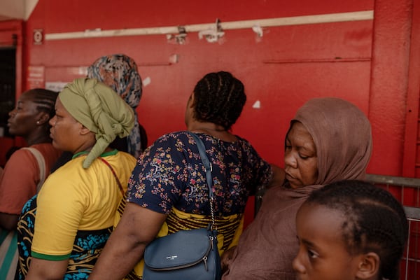 Women wait for supplies to be delivered at a supermarket in Mamoudzou, Mayotte, Friday, Dec. 20, 2024. (AP Photo/Adrienne Surprenant)