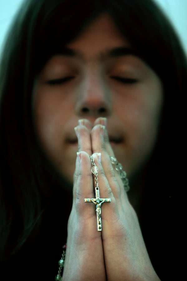 FILE- A young Kosovar Albanian Catholic prays during a Sunday mass for Pope John Paul II in the St. Anthony's Catholic church of Pristina, Kosovo, Sunday, April 3, 2005. (AP Photo/ Visar Kryeziu)