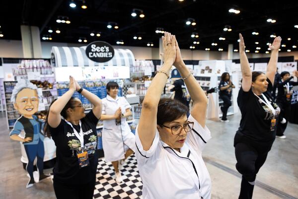 Marcy Gomez of Pasadena, Cal., does yoga with fellow See's Candies employees before doors open to shareholders at CHI Health Center Omaha for the Berkshire Hathaway annual meeting Saturday, May 3, 2025, in Omaha, Neb. (AP Photo/Rebecca S. Gratz)